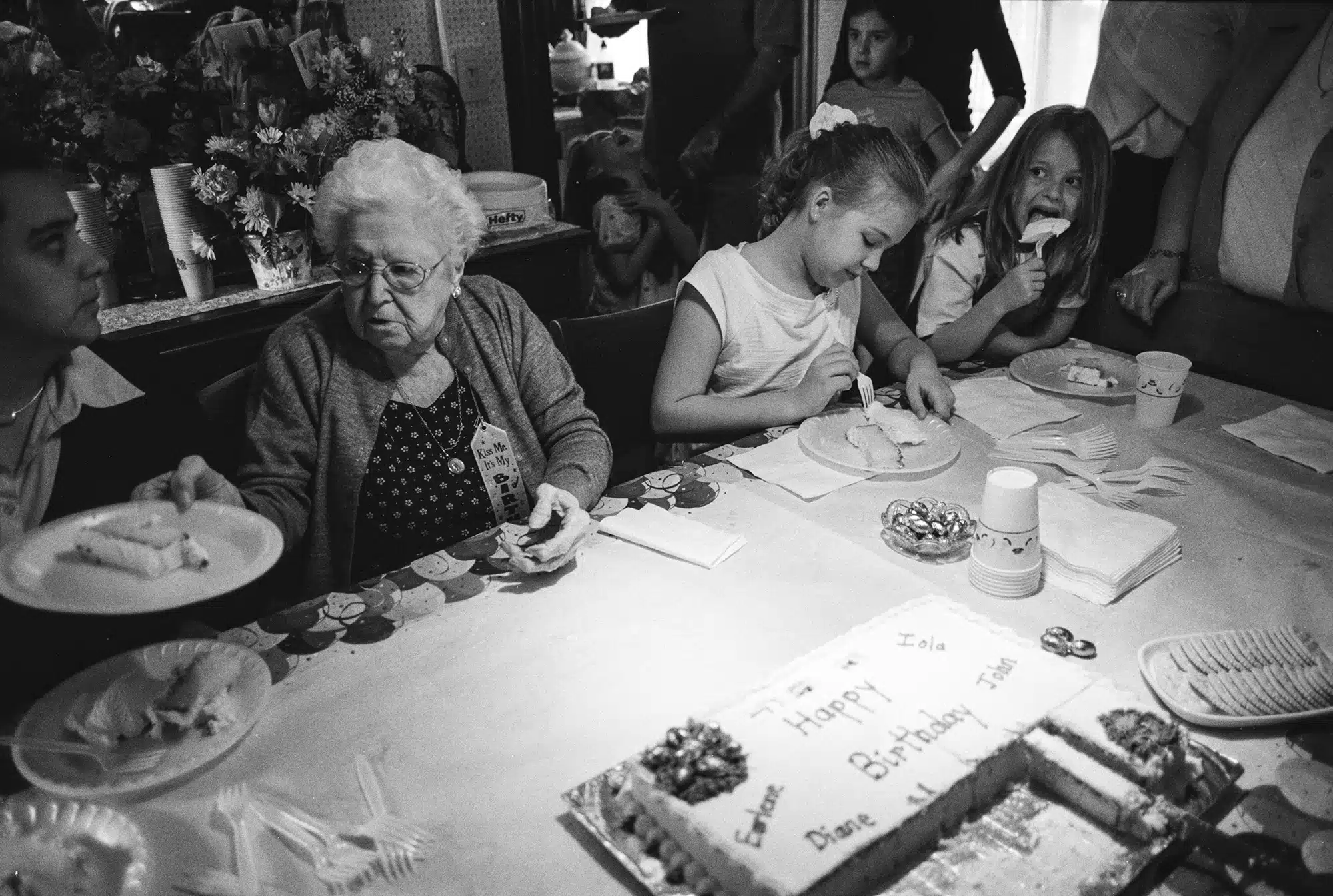 103rd Birthday - 2004 "A particular favorite photo of mine. I was inspired. I had just come back from Sicily where I studied with Master photographer Ernesto Bazan. He taught how to tell more complex stories and to have multiple subjects in your frame that not only add to the story but complete it emotionally as well as compositionally. I heard there was a woman in town turning 103 and was granted permission to photograph the private event. It was an incredibly enjoyable experience and once all the festivities began no one noticed me anymore, which is exactly what I wanted. This was black and white film, and I remember shooting two rolls of this scene. I kept a watchful eye on everyone’s movement and I adjusted my position to be sure to fill each space with a face or detail. There were several good ones but this one has it all -‐ from the woman on the left gazing into the frame to the girl on the right with the huge piece of cake going into her mouth to the the girl in the back with her arms crossed on her chest having a melt down and all the details in just the right place. And, I love how the 103 year old birthday girl is the one cutting and serving the cake!"