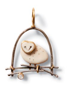 An owl pendant Bach created from cow bone and detailed with sterling silver and gold.