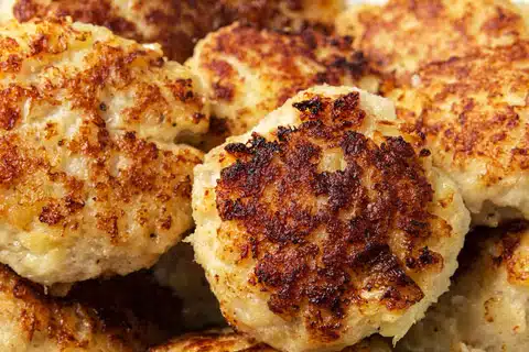 Close-up of several golden-brown, crispy fried meatballs piled together.
