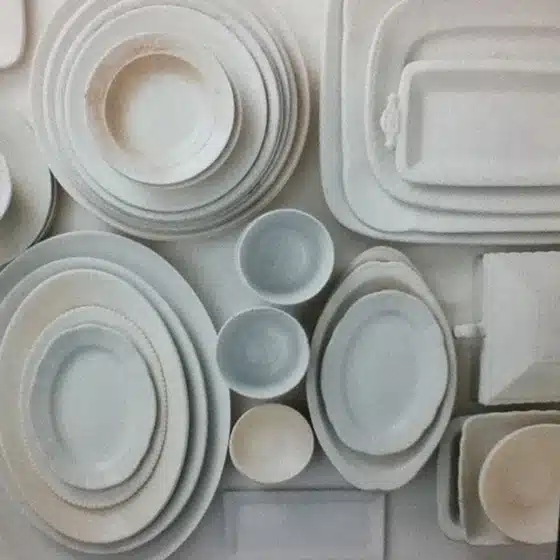Various white ceramic plates, bowls, and platters of different shapes and sizes arranged in an orderly fashion.