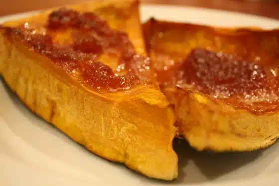 Two slices of toasted bread with a layer of jam on a white plate.