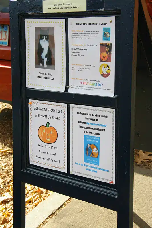 Information board displaying upcoming events. The top-left section features a cat named Boswell. Other sections advertise a Halloween story hour, an author event with Tim Patrick Faulkner, and a family game day.