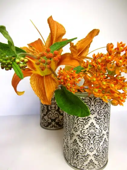 Two intricately patterned vases with orange flowers and green leaves against a plain white background.