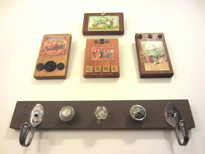 Wall-mounted wooden plaques with various decorations and a lower wooden rack featuring different styles of hooks and knobs.