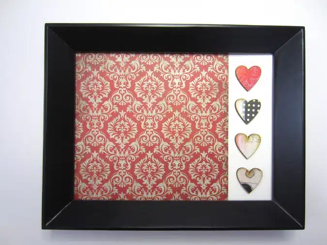 A black frame displays a red and white patterned background with four heart-shaped decorations on the right side.