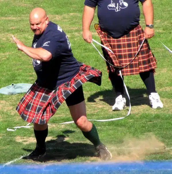 Burly men hurl heavy objects across the field in a display of concentration and strength.