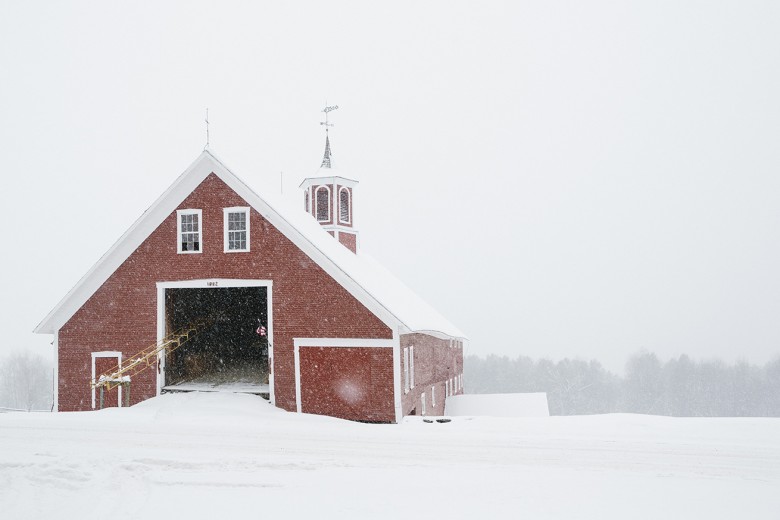The classic red barn at Mountain Valley Farm enveloped in freshly falling snow.