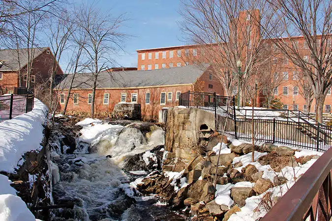 Historic mill buildings curve along the Powow River.