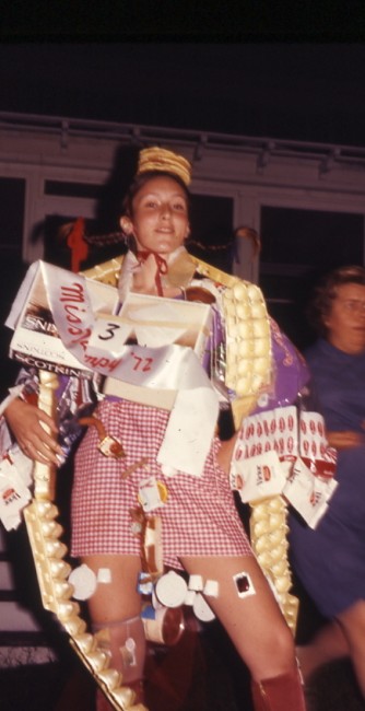 A 1972 Miss Dumpy contestant dons a stack of pancakes as a beret, a bread bag cape, an egg carton boa, and a sausage link belt.
