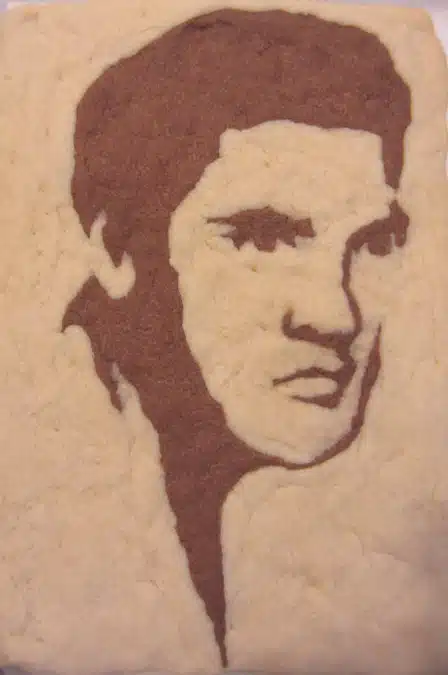 A piece of artwork made in the likeness of a famous person, crafted from a textured material, showing the head and face in profile.