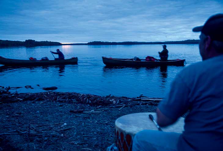 Twilight: “This is Chris Sockalexis drumming us in to Birch Point on the far eastern end of Grand Lake Matagamon. We started this 9-mile stretch as the sun was setting. We paddled for the next 3 hours in utter enchantment (and exhaustion), weaving between pine-covered islands, glassy still water reflecting the blues and purples of the sky as the twilight came on. We heard Chris drumming and singing; the sound carried for miles. We arrived in the last moments of light and enjoyed a feast of moose stew and fresh fiddleheads. This was one of our favorite hours of the whole trip. And then we fell asleep to the sound of loons calling to each other all night long. Truly magical!”