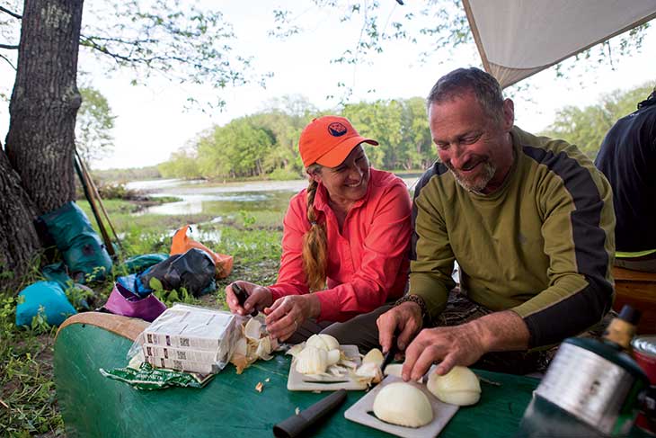 Guide Matt Polstein, NEOC founder and head dinner cook on the trip, uses an overturned canoe as a table to chop onions as he chats with Shannon Leroy of the Appalachian Mountain Club. “Eating great meals in the wilderness was such a large part of the enjoyment of the trip,” the L.O.G. wrote. “This is what makes a Maine guided trip so worth the money—guides who know how to cook in the wild.”