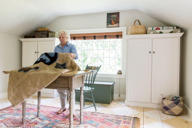 Tammy examines a rug-hooking project in her second-floor craft room, home to sweeping views of the backyard.