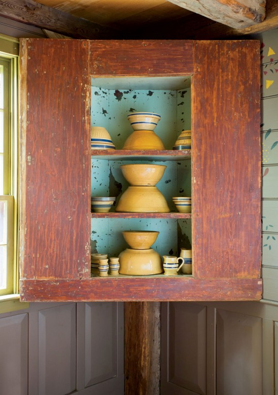 Stacked yellowware decorates a corner cupboard in the dining room.