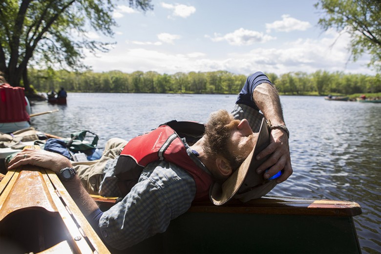 Mike Wilson warms in the sun in the back of his canoe while guides scout out possible campsites. 