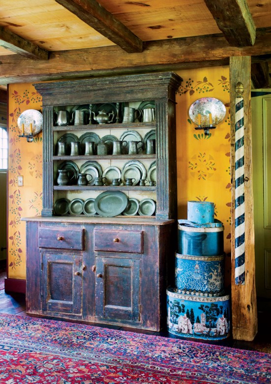 The living-room hutch displays pewter alongside early hatboxes and an old-fashioned barber pole.