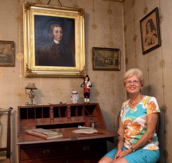 Current owner Ruth Albert has lived in her ances­tral home most of her life; here she poses with the portrait of Dr. Bartlett.