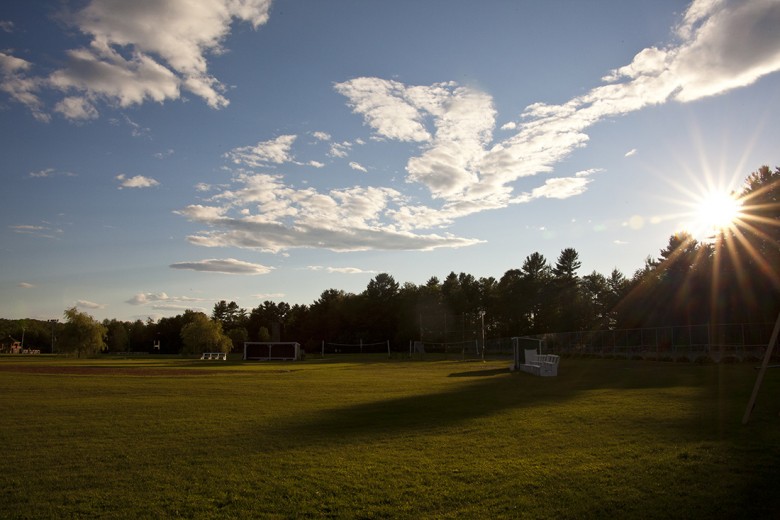 A quiet athletic field bathed in late day light.