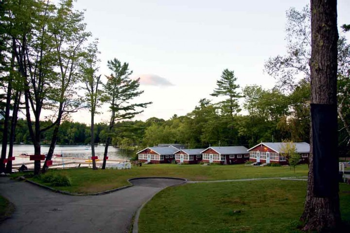 Manitou cabins on the water. The camp was founded in 1947 and today offers a wide range of activities, from sports and adventure experiences to culinary arts, theatre, and yoga.