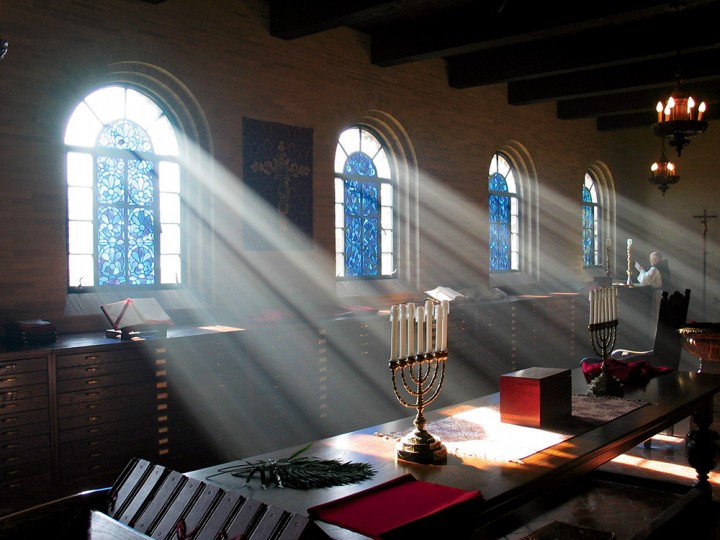 After Mass on Palm Sunday, sunlight streaming through the windows of the sacristy at St. Joseph’s Abbey catches the lingering smoke of incense, while a monk prepares for Holy Week services to come.