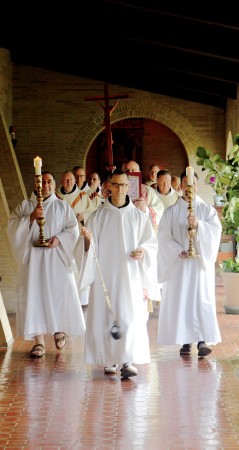 Brother Thomas leads a procession of priests through the Reading Cloister and into the church.