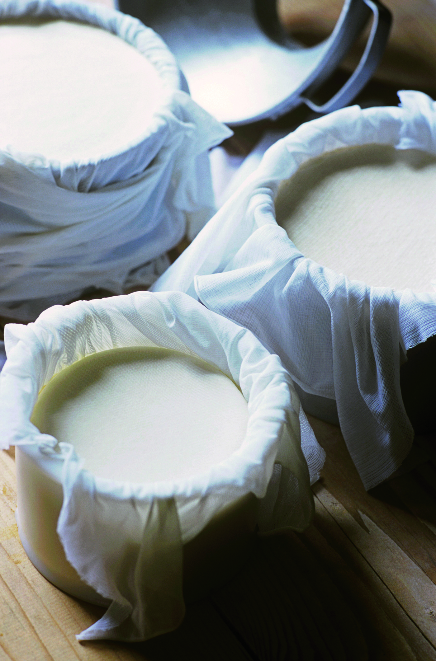 Cheese curds rest in muslin cloths inside round molds. Several New England dairy farms and educational venues offer courses  in cheesemaking for home cooks.
