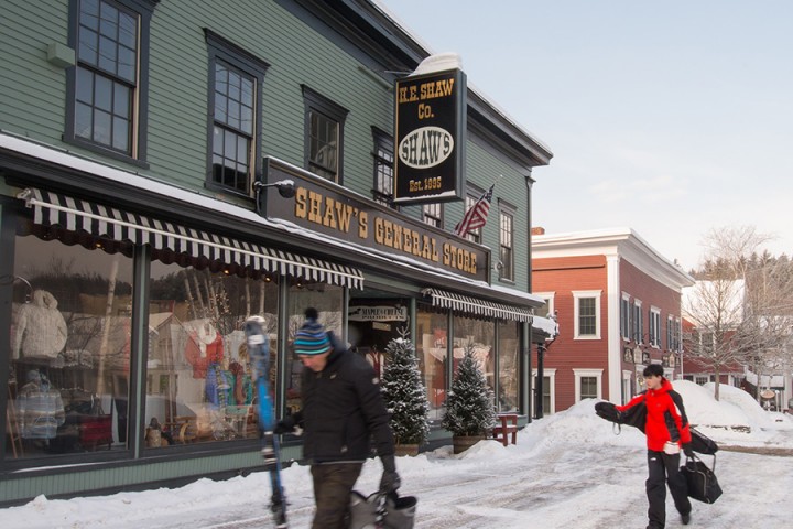 Skiers in motion on Main Street pass Shaw's General Store "helping Vermonters survive in style since 1895". 