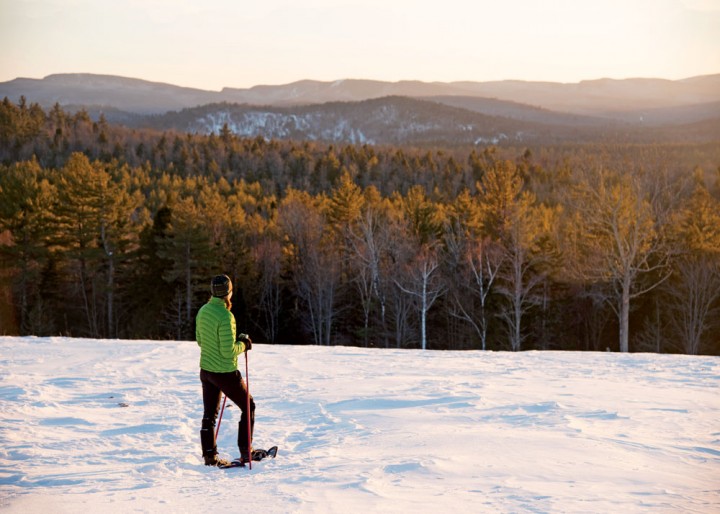 Snowshoer Sheri Harrison pauses in her trek as soft sunshine lights the snow on Paradise Hill in Bethel, Maine. 