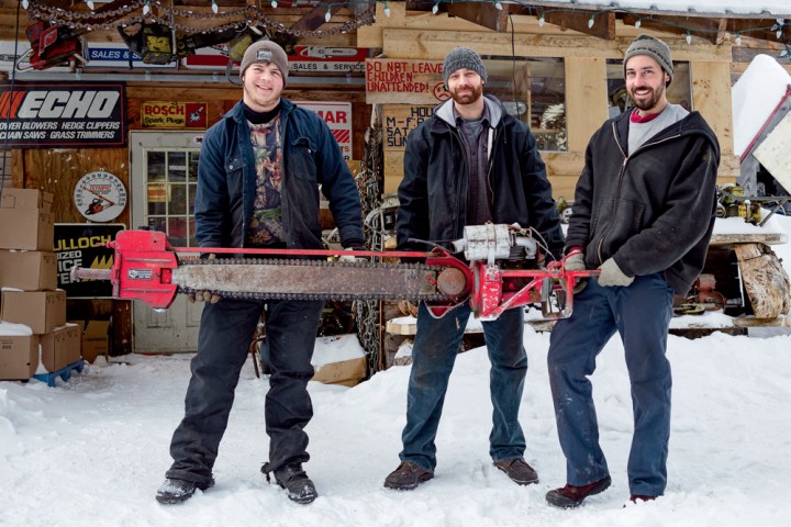 From left, Levi Chase, former employee Alan Grenier, and Scott DesJardins with a 1944 Lombard GS 6 outside The Chainsawr store and chainsaw repair shop in Stannard, Vermont.