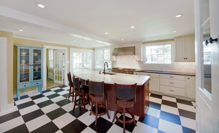 The remodeled, light-filled kitchen features a spacious island, expansive cabinetry, and classic black-and-white checked flooring.