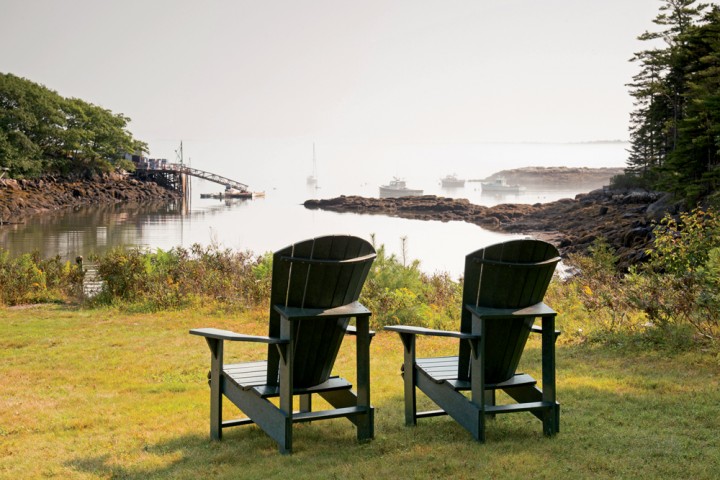 Chairs at Coveside B&B in Georgetown overlook a misty scene, with lobster boats docked just offshore.