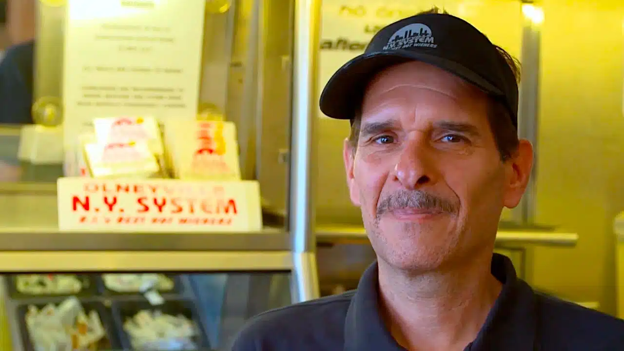 An older man with a hat smiling at the camera.