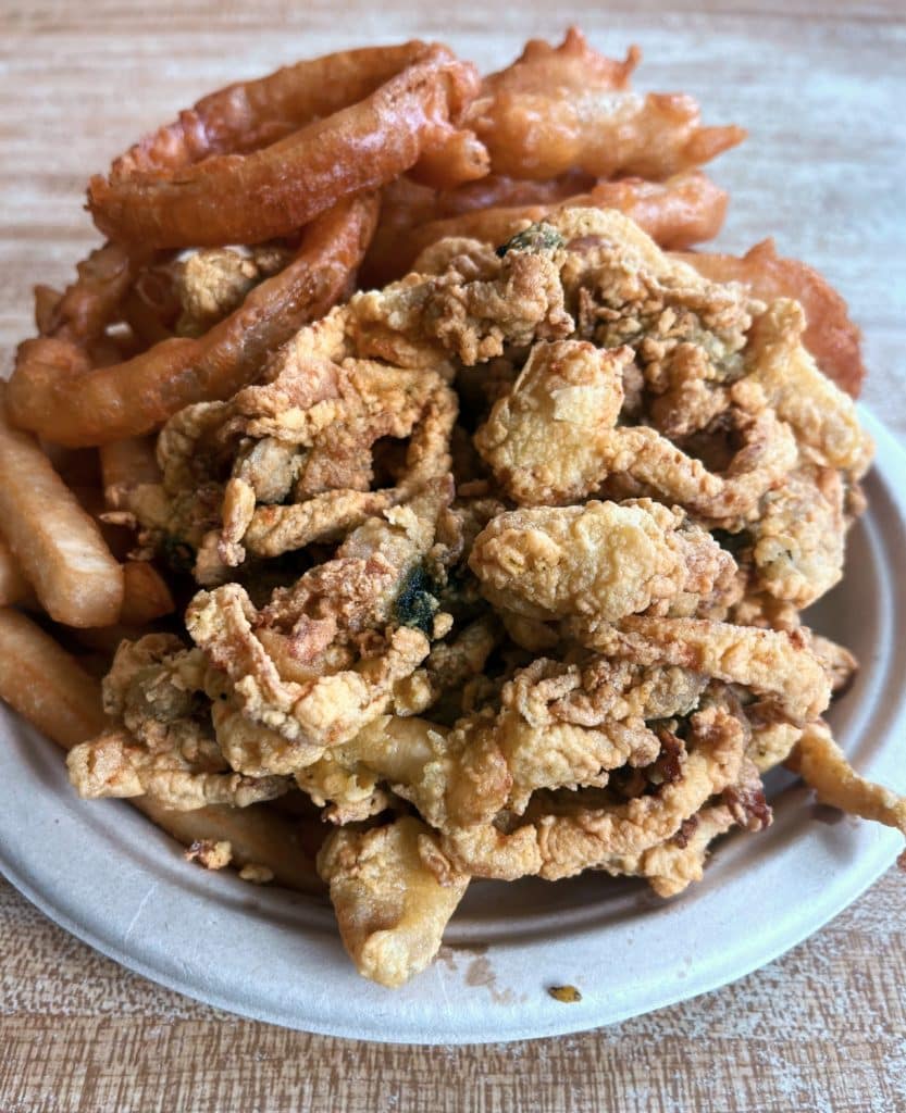 A plate with fried fried clams, onion rings, and French fries from Woodman’s of Essex.