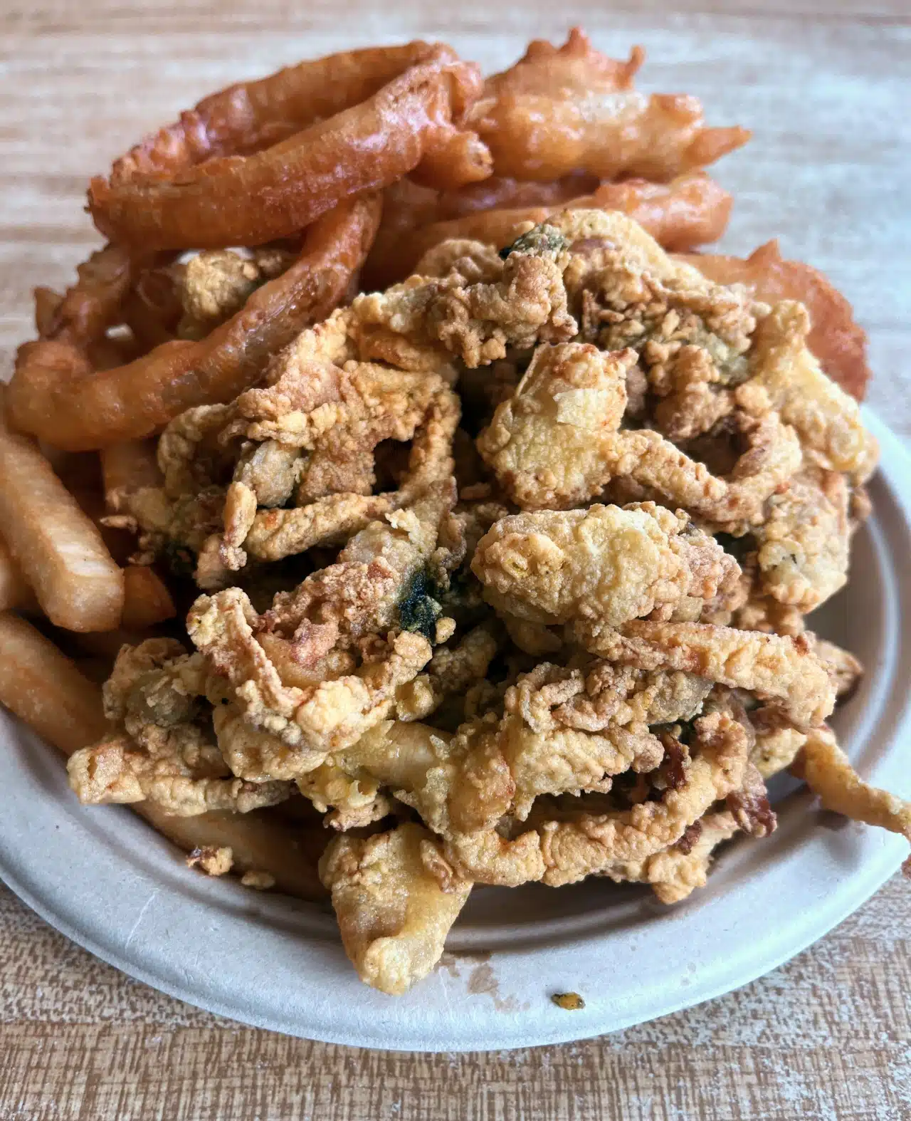 Fried clams recipe. A plate with fried fried clams, onion rings, and French fries from Woodman’s of Essex.