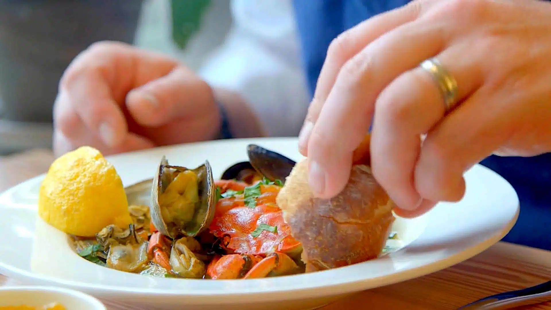 man dipping bread into a seafood boil.