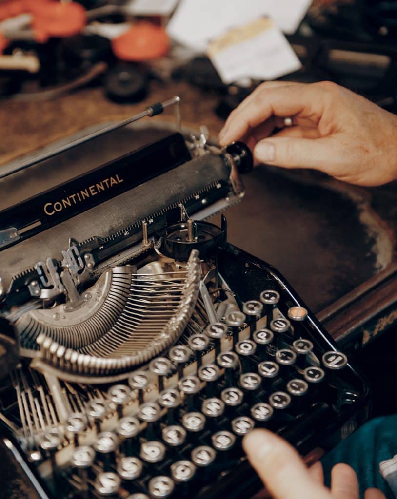 Person adjusting a vintage Continental typewriter with visible keys and mechanism components.