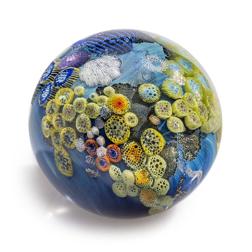 A glass sphere with vibrant multicolored patterns and textures resembling coral reefs and underwater scenes.