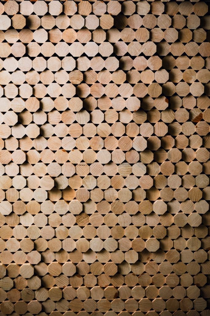 A close-up of neatly stacked hexagonal wooden rods, creating a textured pattern.