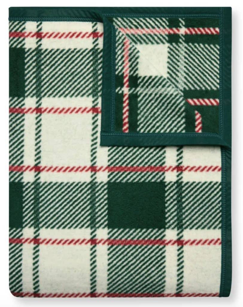 A folded plaid blanket with a green, red, and white checkered pattern and dark green trim.