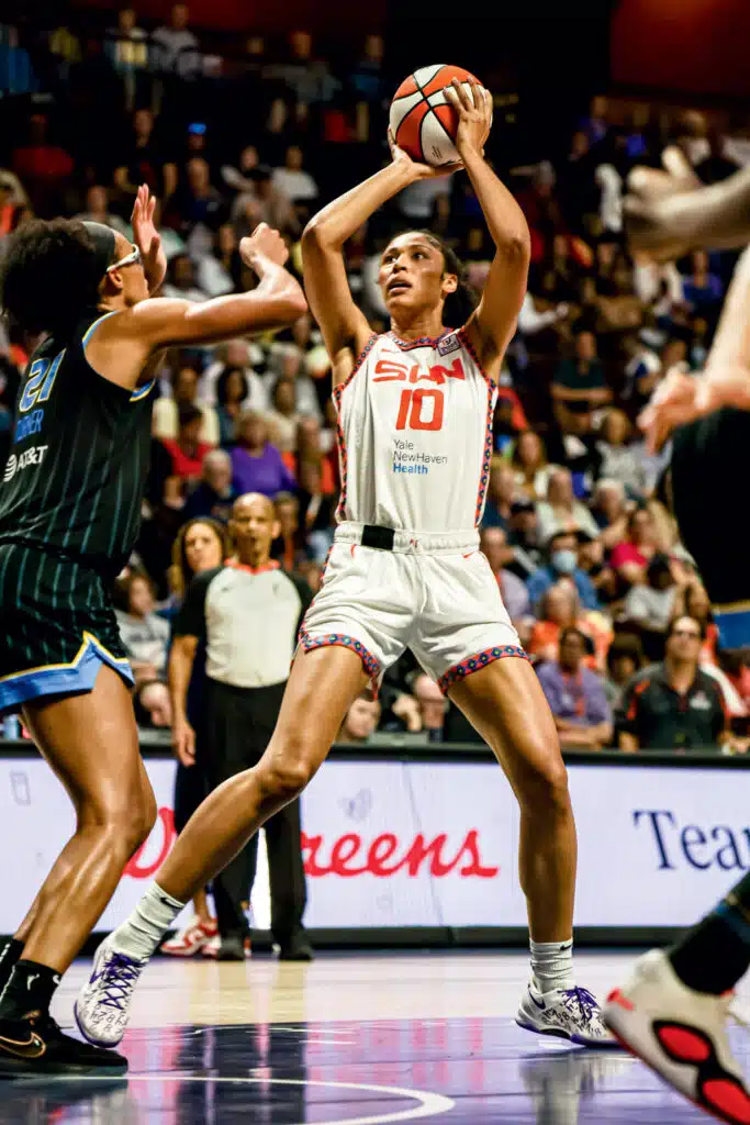 A basketball player in a white jersey prepares to shoot while being defended by an opponent in a black jersey during a game.