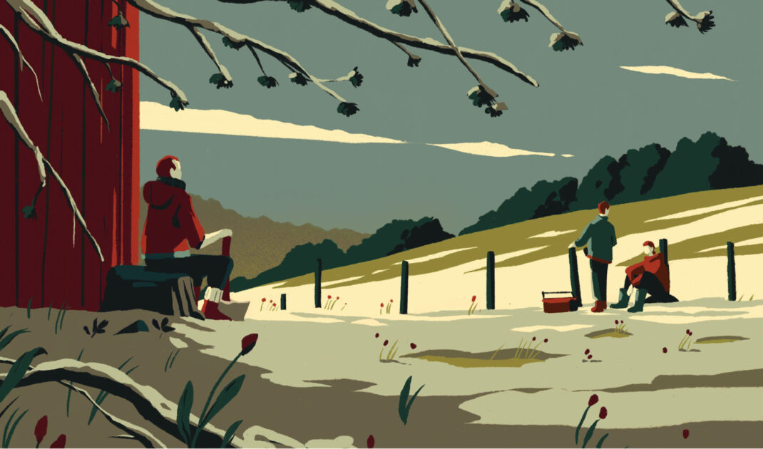 Three people are outdoors near a red building and a fence on a grassy landscape with trees and cloudy skies, with one person seated and two others interacting near a picnic basket.