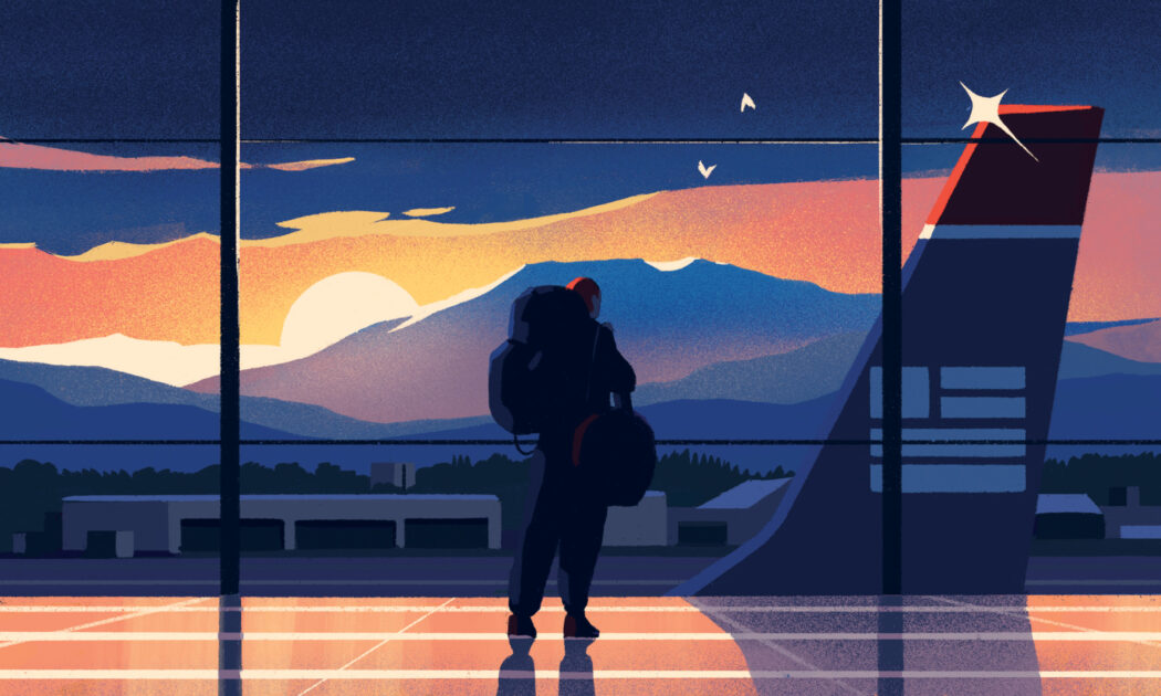 A person with a backpack stands inside an airport terminal, looking out a window at a sunset behind mountains and an airplane tail.