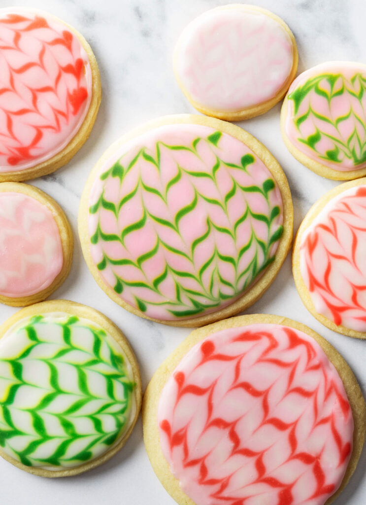 Easy Lemony Shortbread Cookies with colorful marbled icing in pink, green, and red patterns on a white surface.