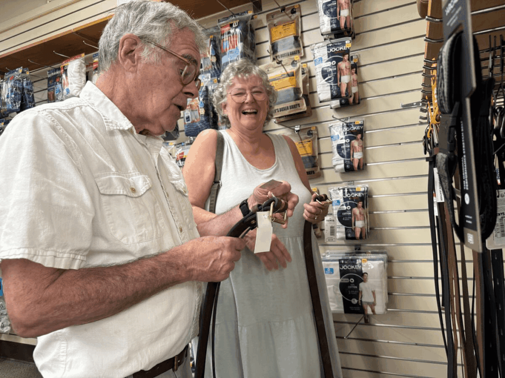 Couple smiling and shopping for belts and other accessories at Renys in Saco, Maine.