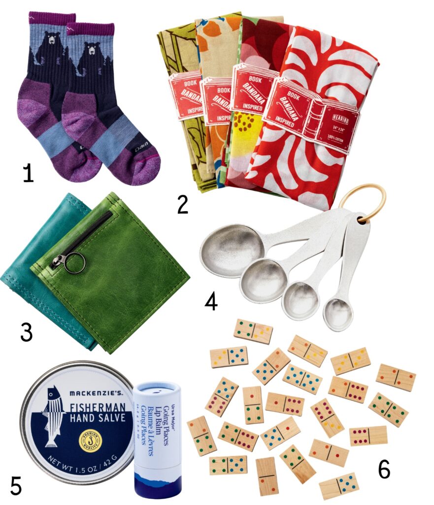 A set of gift items: socks, colorful napkins, leather keychains, measuring spoons, hand salve, and mini dominoes.