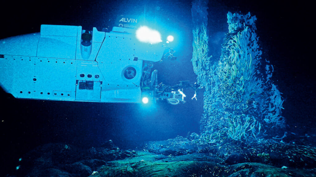 Deep Impact: The Woods Hole Alvin Submersible and Its Legacy of Deep-Sea Discover. A deep-sea submersible explores a dark underwater hydrothermal vent, illuminated by bright lights.