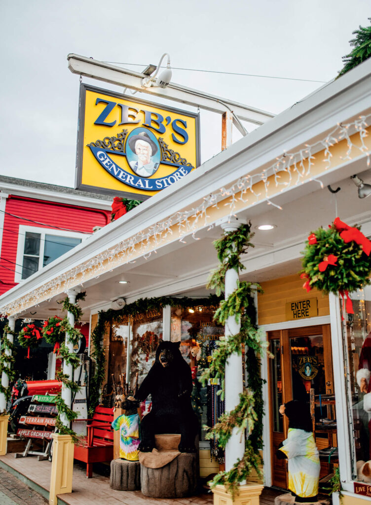 Zeb's General Store decorated with holiday garlands and lights, featuring a bear statue near the entrance.
