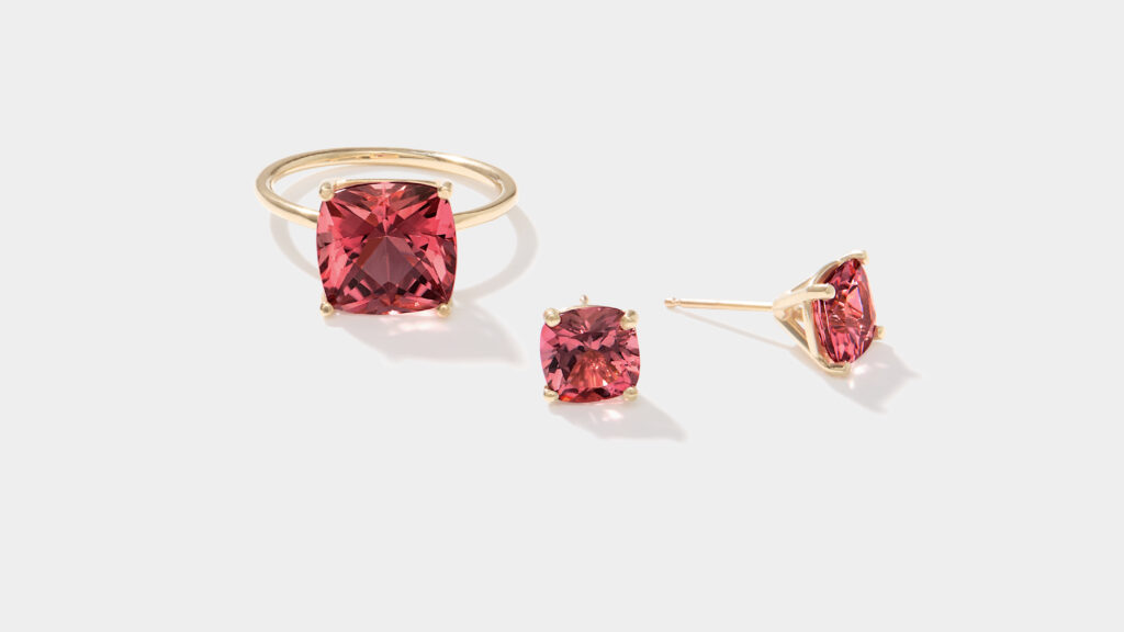 Gold ring and stud earrings set with cushion-cut pink gemstones on a white background.