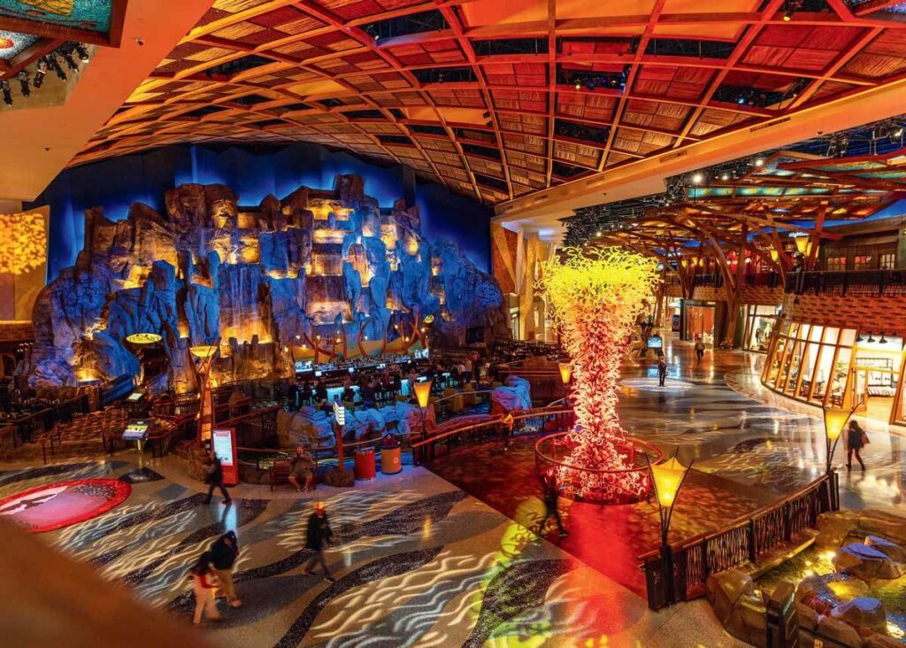 Large, colorful casino interior with rock wall, bright lighting, and a glowing sculptural centerpiece.
