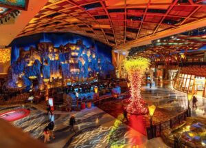 Large, colorful casino interior with rock wall, bright lighting, and a glowing sculptural centerpiece.